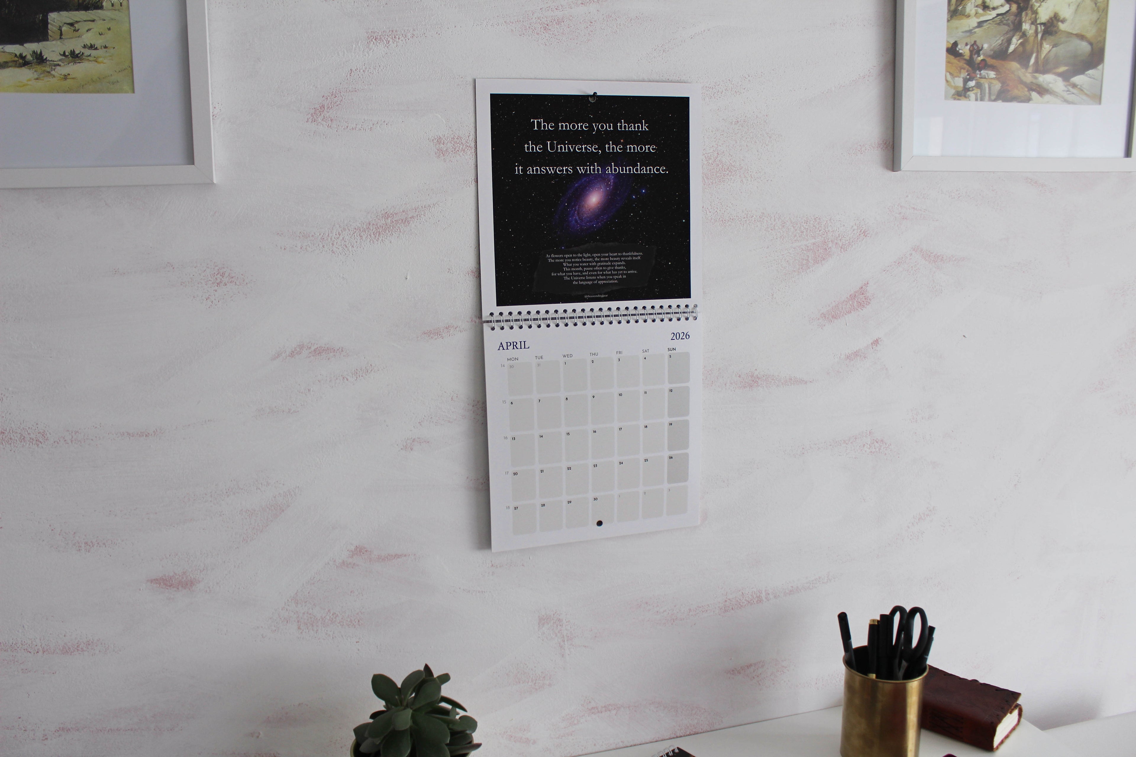 Wall-mounted calendar with inspirational quote on a white wall with decorative elements.
